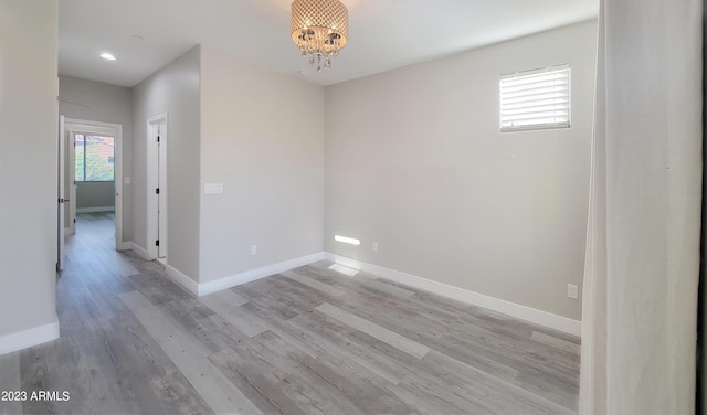 empty room featuring an inviting chandelier and light wood-type flooring