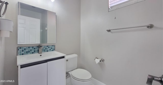 bathroom featuring vanity, toilet, and backsplash