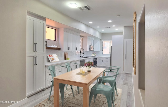 kitchen with sink, decorative backsplash, stainless steel appliances, and light hardwood / wood-style floors