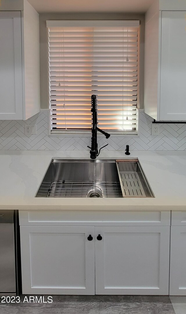 kitchen featuring decorative backsplash, fridge, sink, and white cabinets