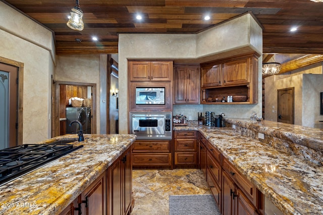 kitchen with wood ceiling, light stone counters, hanging light fixtures, washer and dryer, and stainless steel microwave