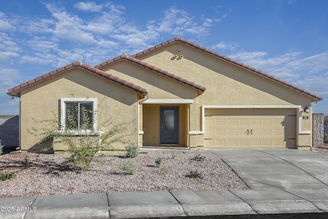 mediterranean / spanish-style home featuring a garage, concrete driveway, a tile roof, and stucco siding