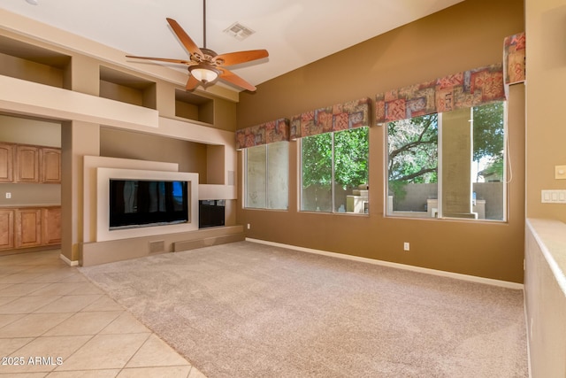 unfurnished living room with light tile patterned floors, baseboards, visible vents, ceiling fan, and light colored carpet