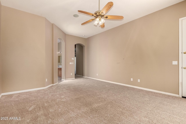 spare room featuring carpet flooring, baseboards, arched walkways, and ceiling fan