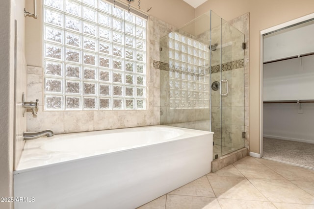 full bathroom featuring tile patterned floors, a healthy amount of sunlight, a stall shower, and a garden tub