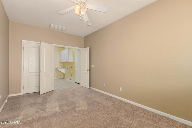 unfurnished bedroom featuring light carpet, visible vents, a ceiling fan, and baseboards