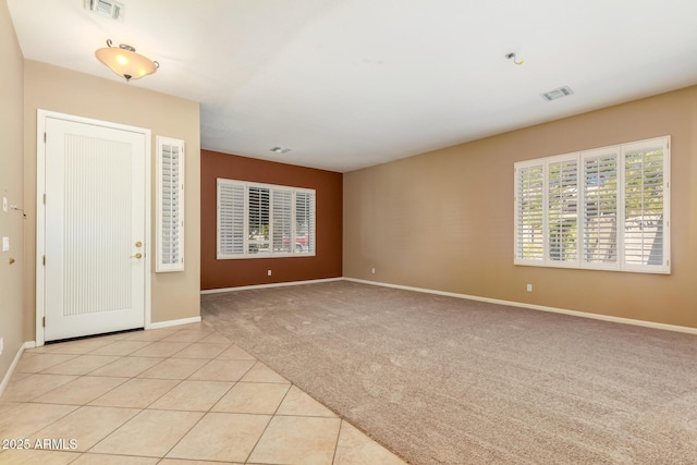 foyer with light tile patterned floors, visible vents, light colored carpet, and baseboards