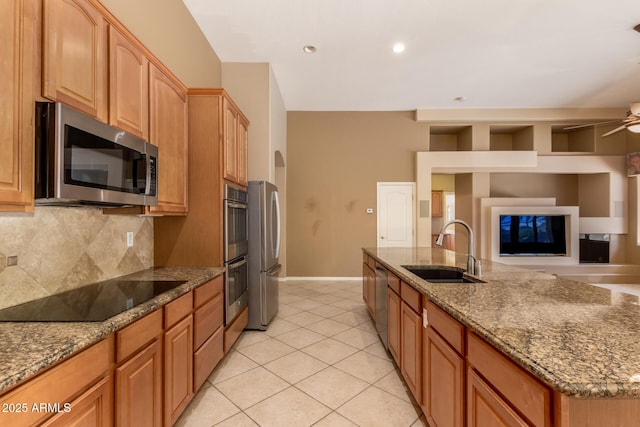 kitchen with a sink, ceiling fan, stainless steel appliances, open floor plan, and backsplash