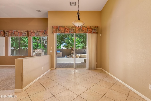 unfurnished room with light tile patterned floors, visible vents, plenty of natural light, and baseboards