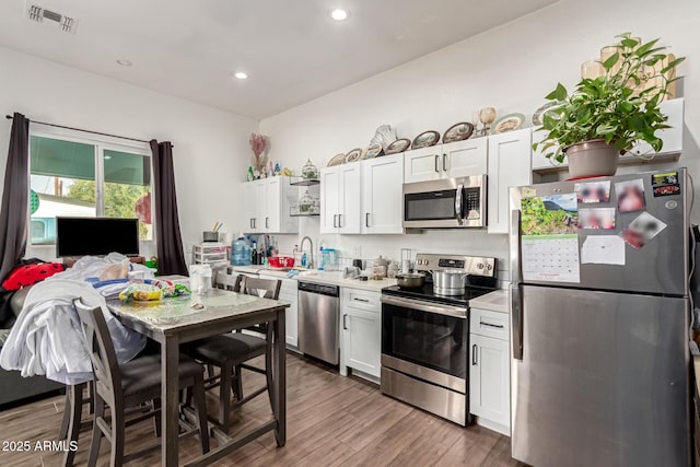 kitchen featuring white cabinets, stainless steel appliances, and dark wood-type flooring