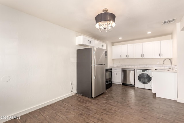 kitchen featuring white cabinets, appliances with stainless steel finishes, and washer / dryer