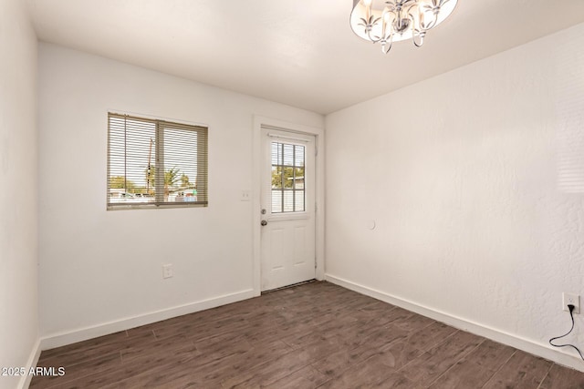 spare room featuring a chandelier and dark hardwood / wood-style floors