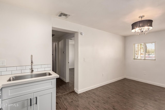 kitchen featuring sink, pendant lighting, a notable chandelier, dark hardwood / wood-style floors, and white cabinetry