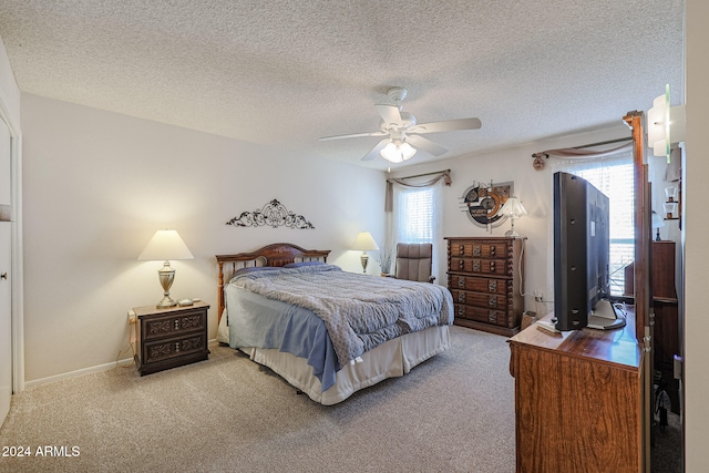 carpeted bedroom featuring ceiling fan and a textured ceiling