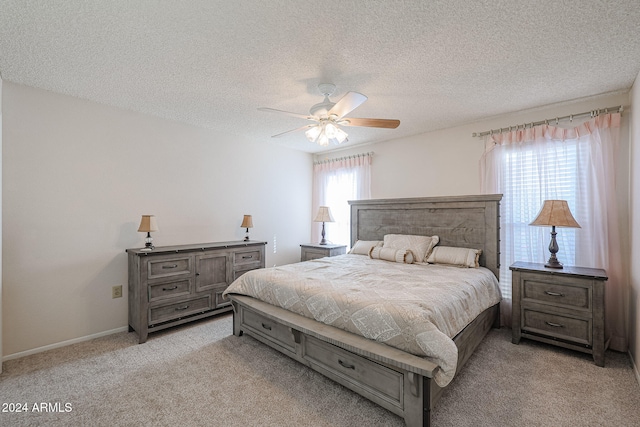 bedroom with ceiling fan, light colored carpet, and a textured ceiling