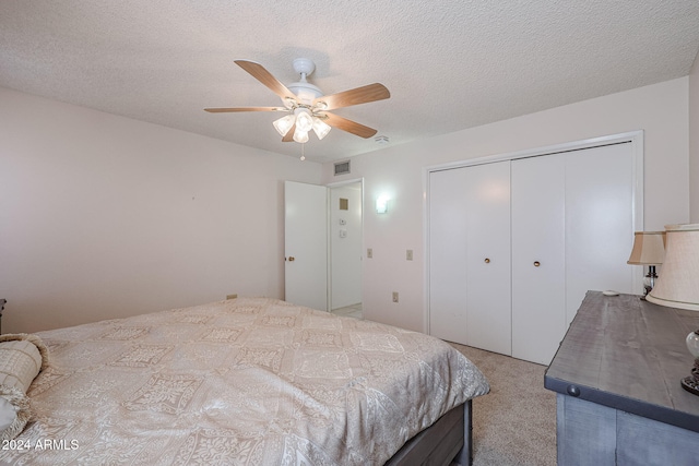 bedroom featuring a textured ceiling, a closet, light colored carpet, and ceiling fan