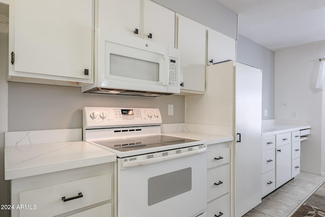 kitchen featuring light stone counters, white cabinets, and white appliances