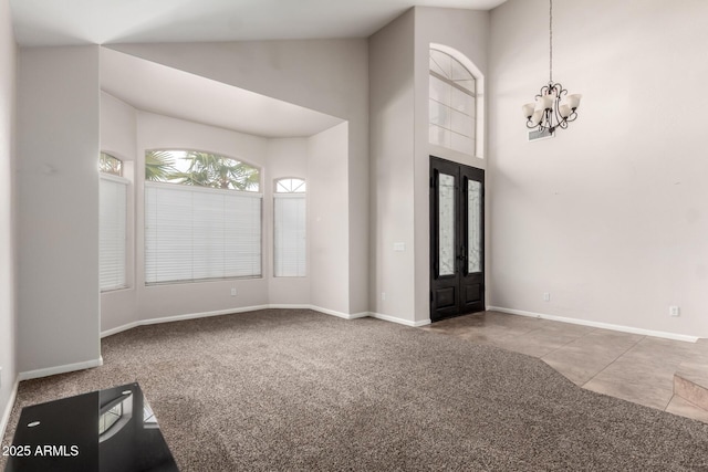 entrance foyer featuring an inviting chandelier, a towering ceiling, carpet flooring, and french doors