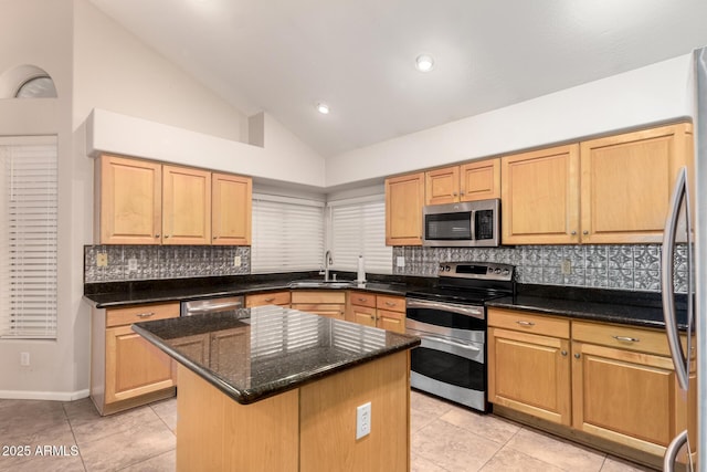 kitchen with sink, a center island, light tile patterned floors, dark stone counters, and stainless steel appliances