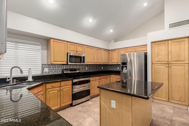 kitchen with sink, dark stone countertops, stainless steel appliances, tasteful backsplash, and a kitchen island