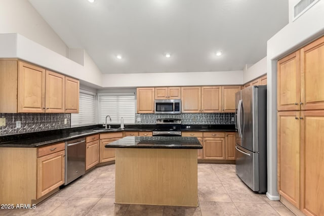 kitchen with appliances with stainless steel finishes, lofted ceiling, sink, dark stone counters, and a center island