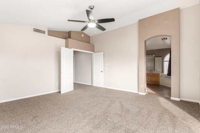 unfurnished bedroom with sink, ensuite bath, ceiling fan, carpet flooring, and vaulted ceiling