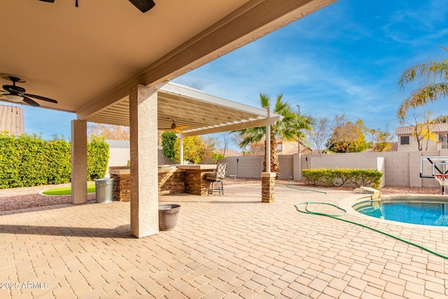 view of swimming pool with a bar, ceiling fan, and a patio area