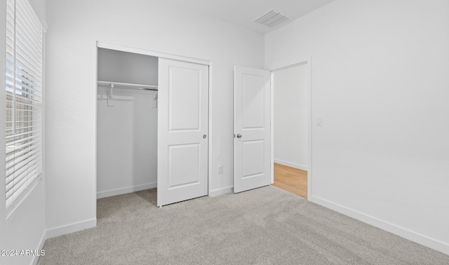 unfurnished bedroom with light carpet and a closet