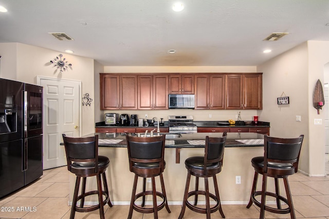 kitchen with stainless steel appliances, visible vents, and light tile patterned flooring