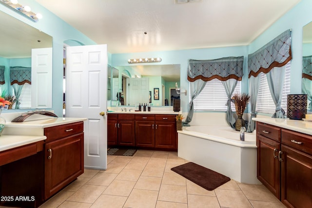 full bath with two vanities, a bath, and tile patterned floors