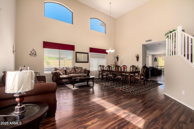living area with wood finished floors, visible vents, a towering ceiling, and stairway