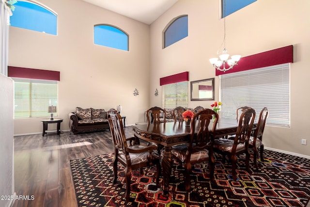 dining area featuring a high ceiling, wood finished floors, a chandelier, and baseboards