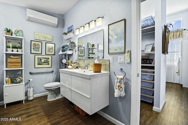 bathroom with wood finished floors, toilet, baseboards, and a wall mounted AC