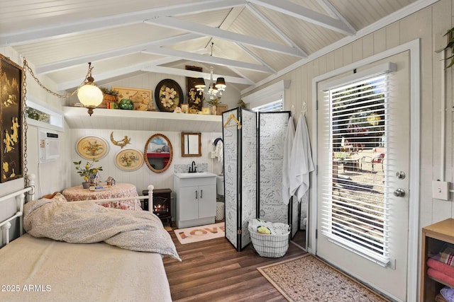 bedroom featuring lofted ceiling with beams, dark wood-style floors, an inviting chandelier, wood walls, and a sink