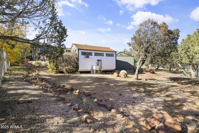 exterior space with a shed, fence, and an outbuilding