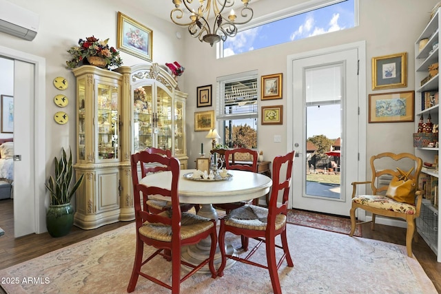 dining area with an AC wall unit, a notable chandelier, and wood finished floors