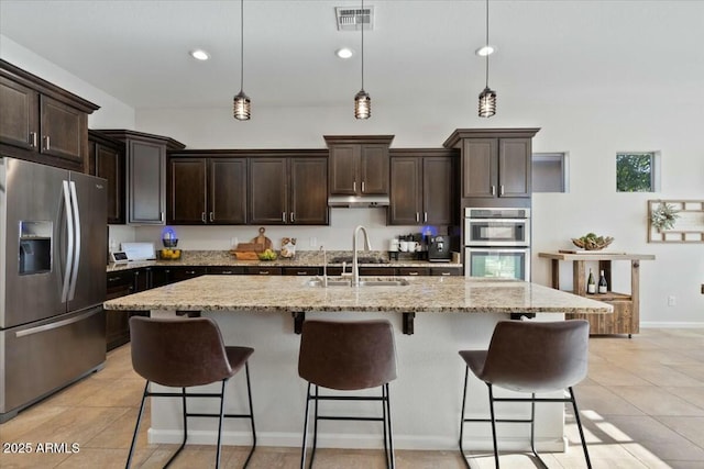 kitchen with dark brown cabinets, visible vents, appliances with stainless steel finishes, under cabinet range hood, and a sink