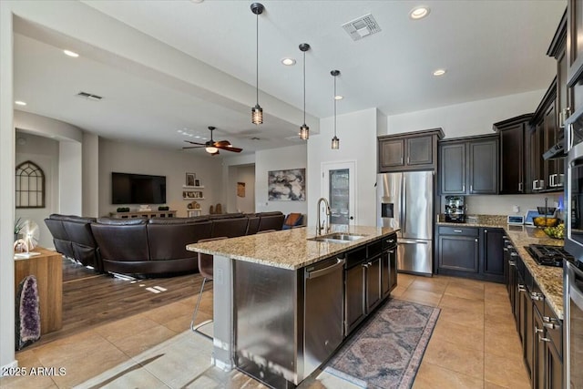 kitchen with stainless steel appliances, visible vents, a sink, and light stone counters