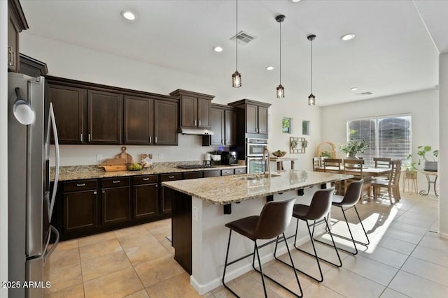 kitchen featuring light tile patterned floors, visible vents, appliances with stainless steel finishes, light stone counters, and under cabinet range hood