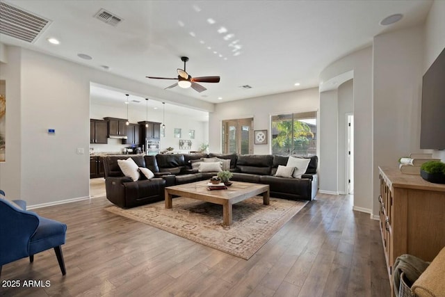 living room featuring visible vents, baseboards, a ceiling fan, and wood finished floors