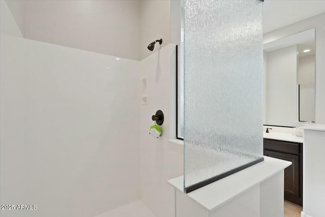 full bath featuring tiled shower and vanity