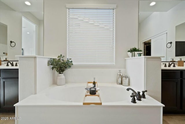 bathroom featuring a sink, two vanities, recessed lighting, and a garden tub