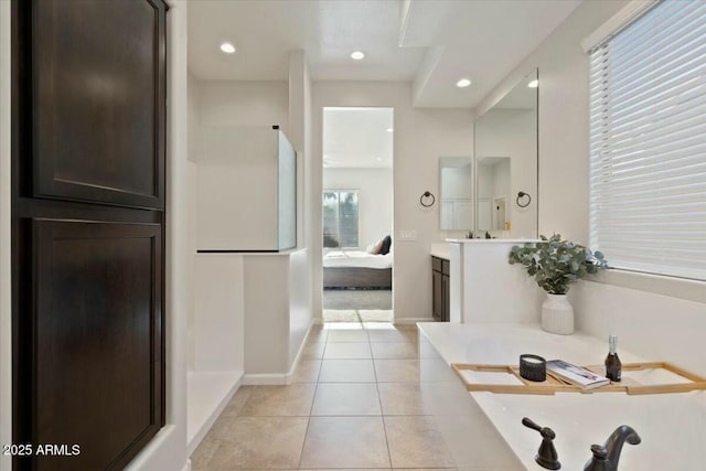 bathroom with a garden tub, ensuite bath, tile patterned flooring, recessed lighting, and baseboards