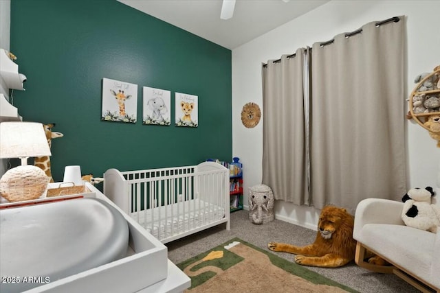 carpeted bedroom with a ceiling fan and a nursery area