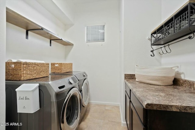 washroom with washing machine and dryer, baseboards, and cabinet space