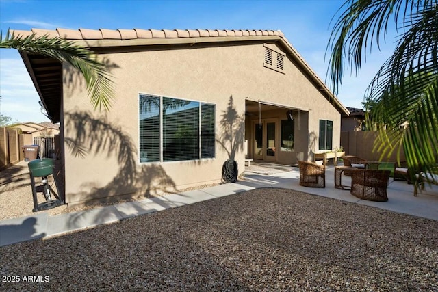 back of house with a patio, stucco siding, fence, and a tile roof