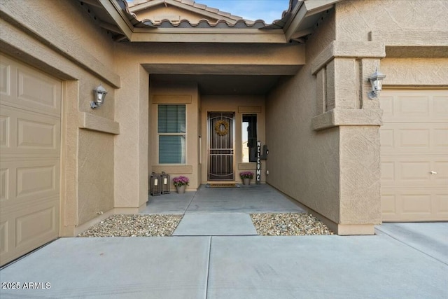 property entrance with a tiled roof, a garage, and stucco siding