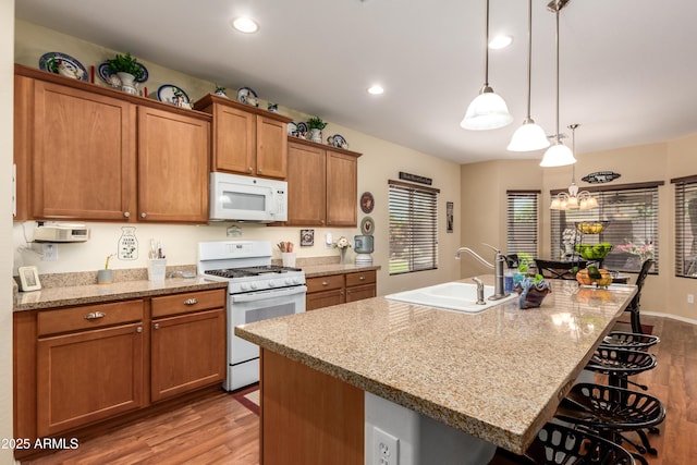 5735 S Cloverdale Ln, Gilbert, AZ 85298 - kitchen with white appliances, light wood-style floors, brown cabinets, a breakfast bar, and recessed lighting