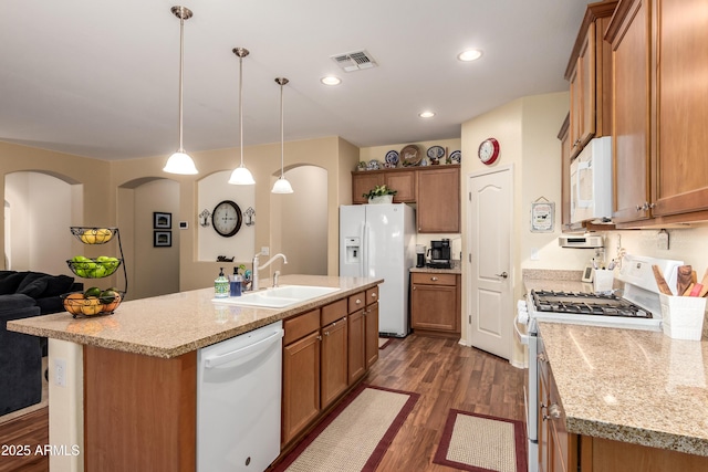5735 S Cloverdale Ln, Gilbert, AZ 85298 - kitchen with white appliances, dark wood finished floors, brown cabinets, an island with sink, and open floor plan