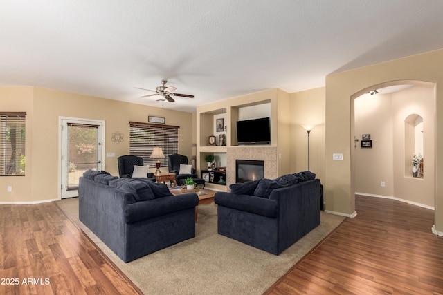 5735 S Cloverdale Ln, Gilbert, AZ 85298 - living area with wood finished floors, a ceiling fan, a tile fireplace, and built in shelves